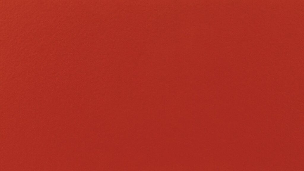 A solid, vibrant red background fills the entire frame. The texture is smooth and unbroken, with no patterns, objects, or variations in color.