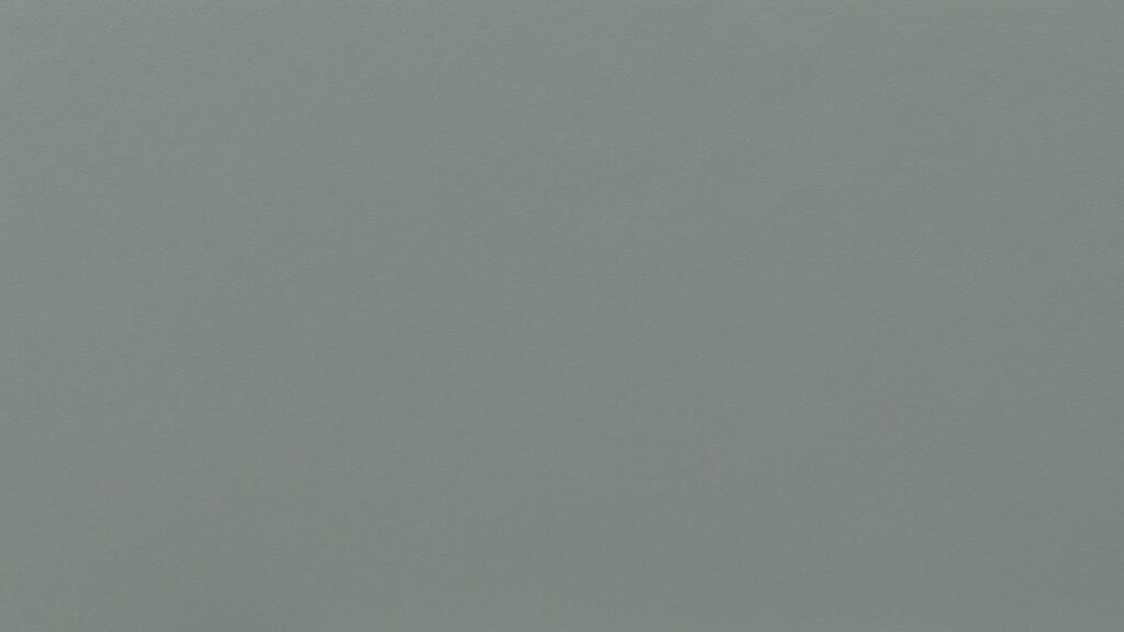 A seamless, solid color background in a light, muted blue hue. The surface appears smooth with a slight texture, giving it a subtle, soft appearance.