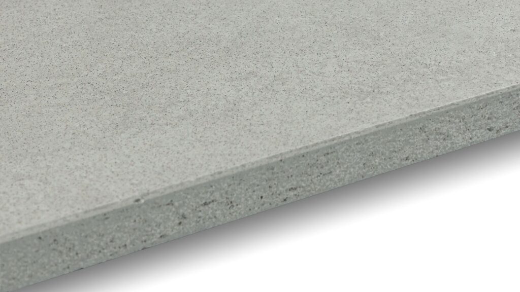 A close-up view of a smooth cement board, showing its thin, flat, and gray surface with subtle textures and edges. The image captures the detailed texture and finish of the construction material against a plain white background.