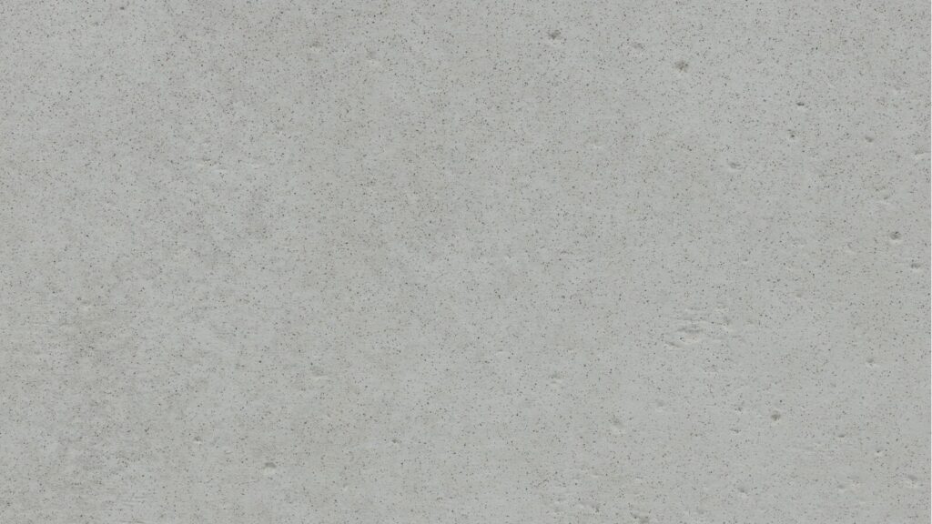 A close-up image of a light gray concrete wall. The surface is rough with scattered small pits and imperfections, giving it a textured appearance.